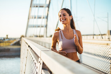 Smiling Woman Jogging on a Modern Bridge During a Morning Workout