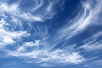White, delicate cirrus clouds paint dynamic swirls against a vibrant blue sky, creating a captivating display of nature's artistry
