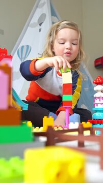 A young child and mother playing with colorful building blocks in a cozy indoor setting. Warm family bonding, creativity, and childhood development in a playful and loving home environment.