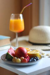 Glass of cocktail, straw hat, sunglasses, books, fresh fruit, chocolate and accessories. Summer essentials on the table. Selective focus.