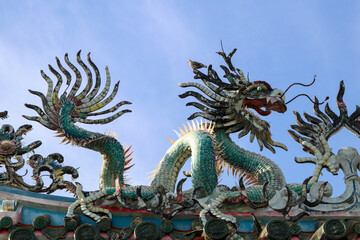 A beautifully crafted green dragon statue decorates the roof of a traditional building, showcasing intricate design and bold cultural symbolism.