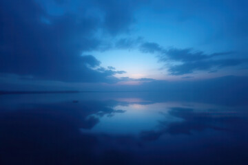 Fototapeta premium Tranquil Afterglow Scene: Soft Silhouettes in Blue and Black Hues, Fading Sky with Delicate Dim Light