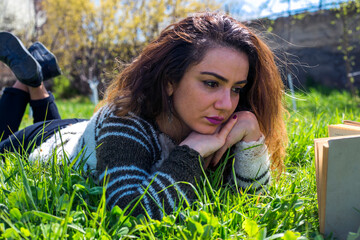 Beautiful girl lies on meadow and reads the book