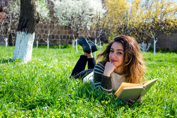 Beautiful girl lies on meadow and reads the book