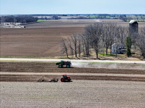 A Self-Propelled Spreader a tractor discing and two other tractors in the distant farm fields all preping the fields for spring planting.