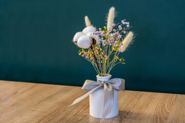 Bouquet of dried plants in vase on wooden table.