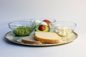 Healthy meal consisting of toast, avocado and boiled eggs arranged on a plate