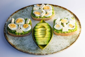 Healthy meal consisting of toast, avocado and boiled eggs arranged on a plate