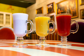 Various drinks in glasses in a restaurant. Tomato juice, orange juice, milkshake.