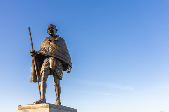 Bronze statue of Mahatma Gandhi holding a staff, set against a clear blue sky. Utrecht, the Netherlands. 8 April 2025.