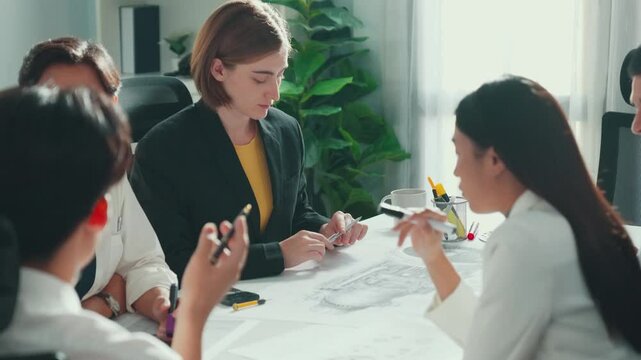 Business woman working and discussing about house model while businessman handed document about architectural model to investor sitting at meeting table with blueprint scattering around. Alimentation.