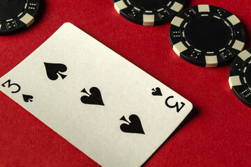 A game of poker is underway with players contemplating their next moves. A three of spades lies...