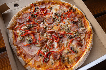 Pizza with ham, sausages, tomato sauce, mozzarella, mushrooms, bell pepper, olives