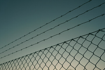 Close-up of barbed wire fence against the sky