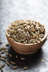 Indian spice fennel in wooden bowl close-up on gray background, vertical macro shot