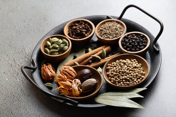 Set of spices for traditional Garam masala mixture. Variety of whole Indian spices on a gray background.