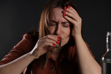 Alcohol addiction. Miserable woman drinking vodka in dark