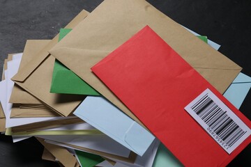 Stack of different paper envelopes on black table, above view. Post office