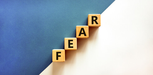 Obraz premium Fear symbol. Concept word Fear on beautiful wooden blocks. Beautiful white and blue background. Business, lifestyle and fear concept. Copy space.