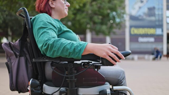 Woman using electric wheelchair controller outdoors