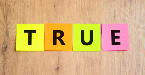 True symbol. Concept word True on beautiful colored paper. Beautiful wooden table wooden...