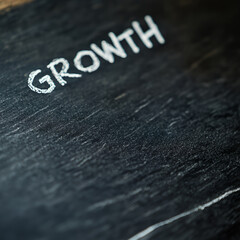Fototapeta premium The word 'GROWTH' handwritten on a dark chalkboard surface.