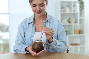Woman with traditional yerba mate tea at table indoors