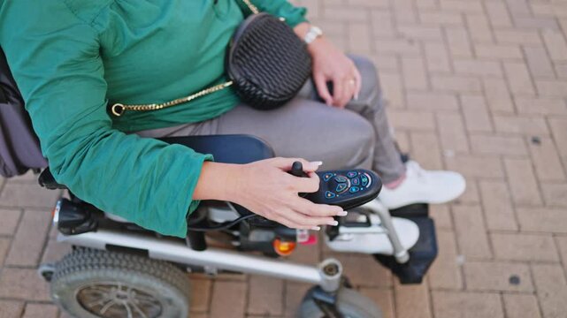 Woman using electric wheelchair control outdoors