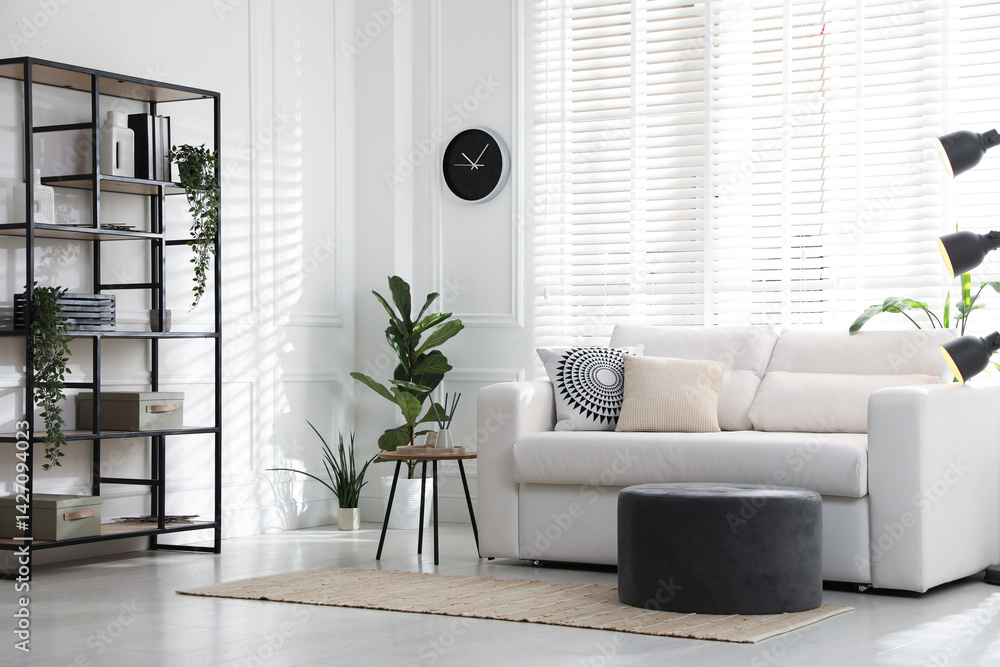 Poster stylish shelving unit with decor and sofa in room