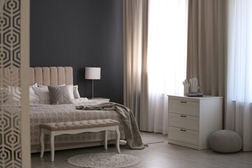 Beautiful curtains on window in stylish bedroom interior
