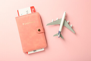 Passport with ticket and plane model on pink background, flat lay