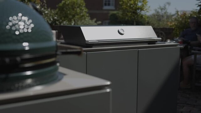 A grill is sitting on a counter next to another grill. The first grill is green and white, while the second one is black. The two grills are placed side by side