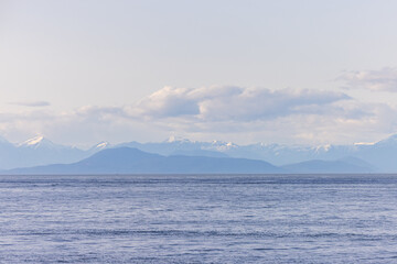 Scenic View of Snowcapped Mountains over Calm Ocean Surface in BC, Canada