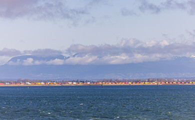 Freight Train Along Coastline Beneath Mountains and Clouds in Strait of Georgia