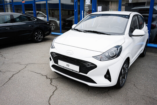 Modern white compact hatchback Hyundai i10 car parked in front of a dealership building