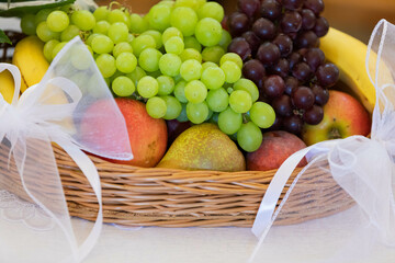 A delightful Fresh Fruit Basket with Green and Purple Grapes, Apples, and Bananas