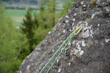 Detailed view of climbing rope and metal anchor on rocky cliff. Ideal for blogs, tutorials, or educational content on mountaineering, rock climbing and outdoor safety.