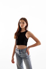 Young model poses confidently against a plain background in casual attire in a photography studio