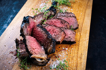 Traditional grilled barbecue dry aged tomahawk beef steak meat with salt and fresh herbs served and...