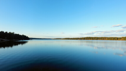 Obraz premium Tranquil lake reflecting a clear blue sky.