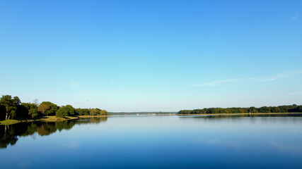 Fototapeta premium Tranquil lake reflecting a clear blue sky.