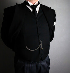 Butler or Hotel Concierge in Formal Black Suit Standing With Hands Behind Back in Dignified Fashion. Professional Hospitality and Courteous Service.