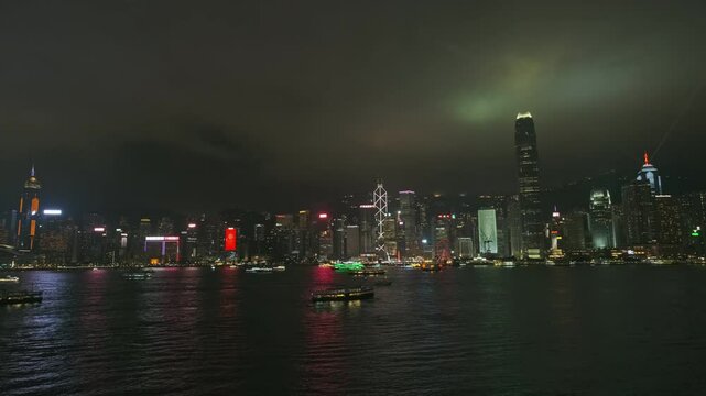 Light show in Hong Kong at night. Victoria Harbour with boats and skyscrapers, Hong Kong Central, time lapse, 4k
