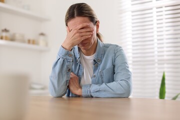 Naklejka premium Depressed mature woman at table in room
