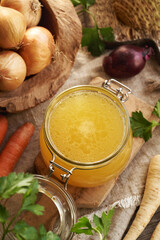 Bone broth in a glass jar with fresh root vegetables