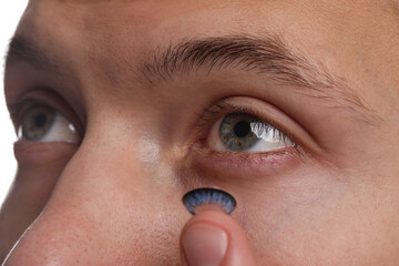Man putting color contact lens in his eye, closeup