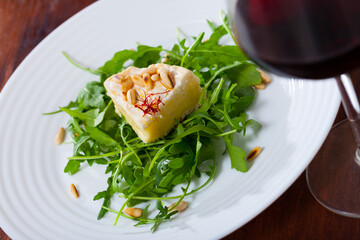 Delicious french cheese camembert garnished with roasted pine nuts and greens