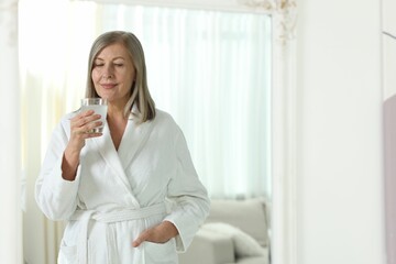 Woman with glass of collagen water at home. Space for text