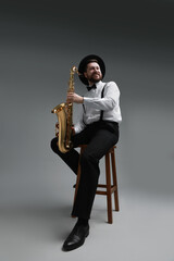 Naklejka premium Professional musician with saxophone on grey background, low angle view