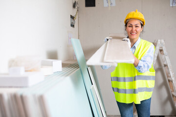 Young adult woman maintenance worker working at renovating object, carrying construction materials
